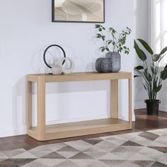 a wooden table sitting on top of a hard wood floor next to a potted plant