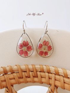 a pair of earrings with flowers on them are sitting on a chair next to a basket