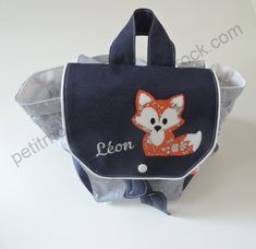 a bag with an embroidered fox on the front and name written across the bottom, sitting on a white surface