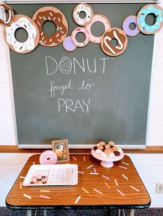 doughnuts are arranged on a table in front of a chalkboard that says donut forget to pray