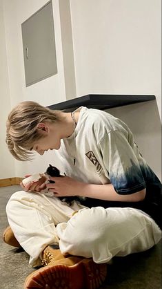 a person sitting on the floor petting a cat