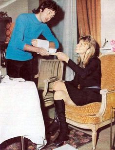 a woman sitting in a chair next to a table with a cup on her lap