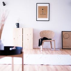 a chair sitting on top of a hard wood floor next to a wall with pictures above it