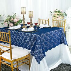 a blue table cloth with white lace on it and two gold chairs at the end