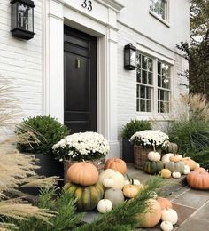 a house with white flowers and pumpkins in the front yard, on instagram