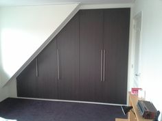 an attic bedroom with built in closets and carpeted flooring