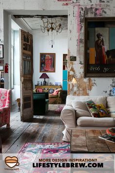 a living room filled with lots of furniture and paintings on the wall next to a doorway