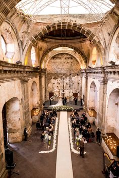 an overhead view of a wedding ceremony in a stone building with white flowers on the aisle