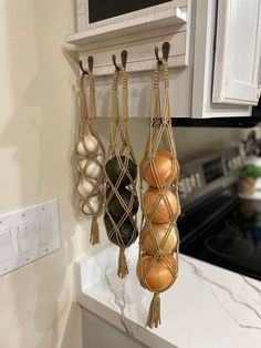 three balls hanging from hooks in a kitchen with marble counter tops and white cabinets behind them