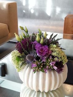 a white vase filled with purple flowers on top of a table