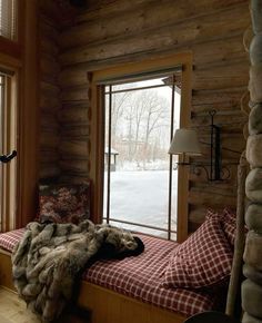 a log cabin bedroom with a window seat and plaid blanket on it's bed