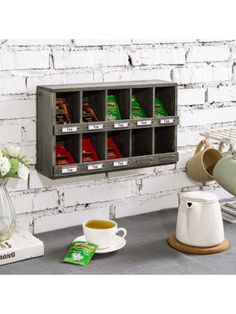 there is a coffee cup and tea pot on the counter next to a rack with cups