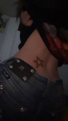 a woman with a star tattoo on her lower back, wearing black jeans and a bandana