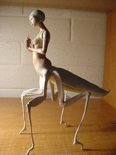 a statue of a woman sitting on top of a wooden table