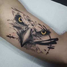 an eagle tattoo on the arm with yellow eyes and black paint splattered over it