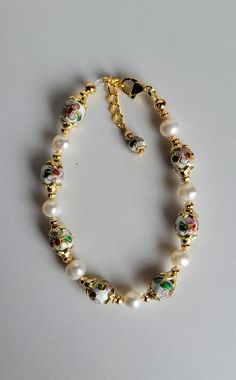 This bracelet is made of round white Cloisonné' beads, white Freshwater pearls and gold plated beads and findings. It has a 1" extension with a beaded drop making it adjustable. It has a lobster claw clasp.  Cloisonné is the technique of creating designs on metal vessels (cloisons) with colored-glass paste placed within enclosures made of copper or bronze wires, which have been bent or hammered into the desired pattern.  Custom Orders are always welcome! Ask about free sizing. Bracelets Design, White Freshwater Pearl, Beads Bracelet, Pink Flower, Bracelet Designs, Lobster Claw, Colored Glass, Custom Orders, Fresh Water