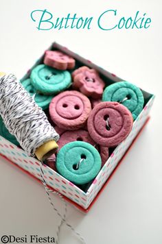 a box filled with different colored buttons next to a spool of thread