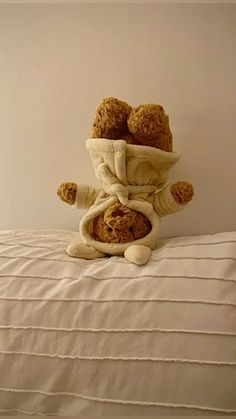 a teddy bear sitting on top of a bed covered in a blanket and some food