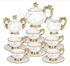 a white and gold tea set with matching saucers