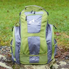 a green backpack sitting on top of a rock