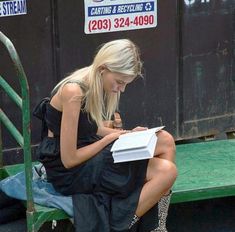 a woman is sitting on a bench and writing with a pen in her hand while wearing leopard boots