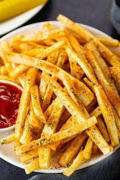 a white plate topped with french fries next to a bowl of ketchup and a banana