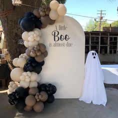 a white tombstone with black and gold balloons on it next to a ghost balloon arch