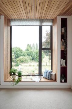 an empty room with a large window and bookshelf on the wall next to it