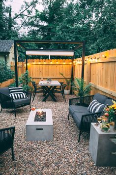 an outdoor patio with seating and fire pit in the center, surrounded by wooden fence