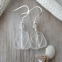 two heart shaped sea glass dangles on a wooden table