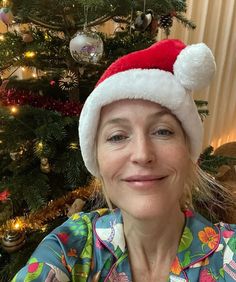 a woman wearing a santa hat in front of a christmas tree