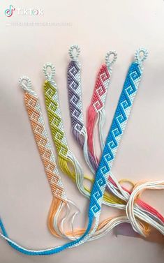 four different colored braided bracelets on a white surface