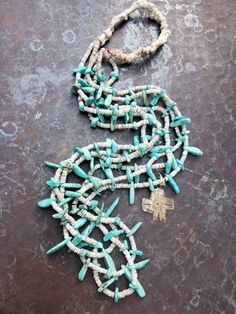 "This incredible necklace features 3 strands of beautiful medium blue turquoise tabs interspersed with heishi. The necklace is strung on red string which is rare, meaning that the wearer of the necklace was an important leader or a medicine man in the Water Way Ceremony. According to the Navajo, red brings moisture blessings to the land. The back is cotton wrapped and comfortable to wear. The silver cross was a later addition, but is made from a coin and stamped on both sides. Ca 1960s Length: 2 Traditional Turquoise Hand Wrapped Jewelry, Southwestern Double Strand Beaded Necklaces, Traditional Turquoise Hand-wrapped Jewelry, White Southwestern Turquoise Necklace Gift, Turquoise Multi-strand Hand Wrapped Jewelry, Adjustable Blue Southwestern Necklace, Southwestern Multi-strand Turquoise Necklace For Jewelry Making, Unique Multi-strand Turquoise Necklace, Bohemian Multi-strand Hand-strung Turquoise Necklace