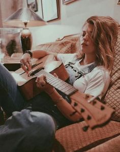 a woman sitting on a couch playing an acoustic guitar