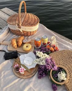 a picnic table with bread, jams and donuts on it next to the water