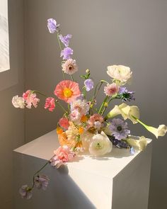 an arrangement of colorful flowers on a white pedestal