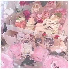 a table topped with lots of cupcakes covered in frosting and pink flowers