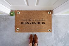 a woman standing in front of a door mat with the words'quentena est benvenidos'written on it