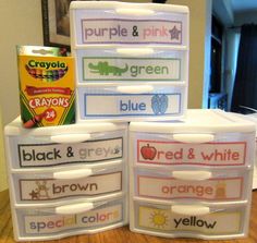 four plastic containers with labels on them sitting on top of a wooden table next to a can of crayons