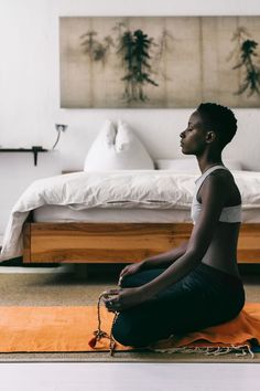 a woman sitting on the floor in front of a bed