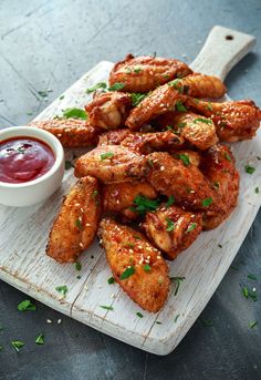 chicken wings with ketchup and sauce on a cutting board, ready to be eaten