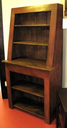 a wooden book shelf sitting on top of a red floor