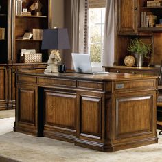 a wooden desk with a laptop on top of it in front of a bookcase