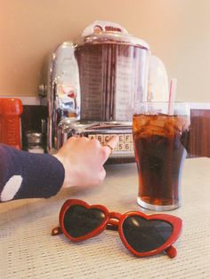 a person wearing heart shaped sunglasses next to a drink