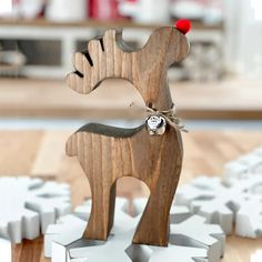 a wooden reindeer ornament sitting on top of snowflakes with a red nose