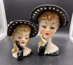 two ceramic figurines with hats on their heads