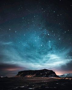 the night sky is filled with stars and clouds, as well as some mountains in the distance