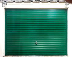 a green garage door in front of a white building