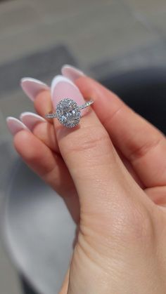 a woman's hand holding a ring with a diamond on it and the middle finger