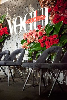 four chairs are lined up in front of a wall with red flowers and the words veggies written on it